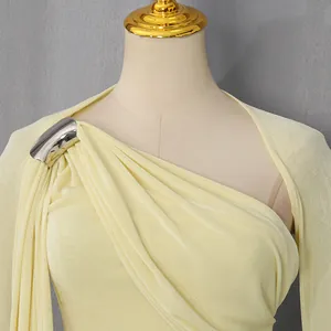 Close-up of elegant light yellow one-shoulder dress with metallic buckle detail