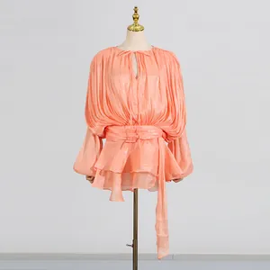 Close-up of elegant apricot pleated mini dress with balloon sleeves and waist tie