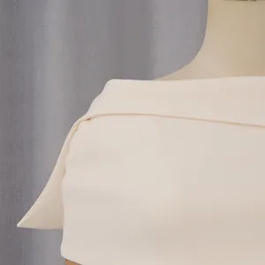 Dettaglio ravvicinato dell'elegante scialle color crema e del design della spalla.