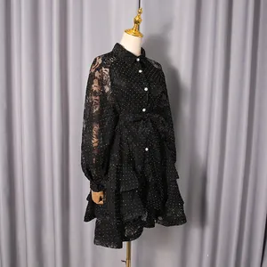 Detailed view of elegant black polka dot dress featuring floral lace and ruffled hem