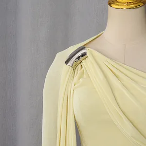 Close-up of elegant light yellow French one-shoulder dress with metallic buckle detail