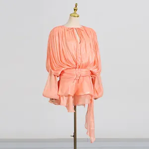Macro detail of peach pleated mini dress with elegant tie-neck and balloon sleeves
