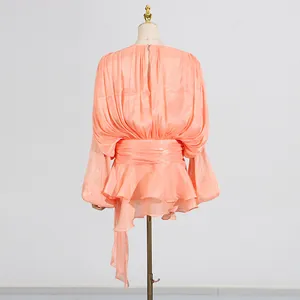 Detailed back view of a peach pleated dress with elegant ruffles and tie-waist design