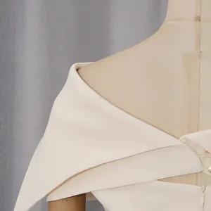 Dettaglio ravvicinato del design elegante con scialle scoperto su un abito boutique crema