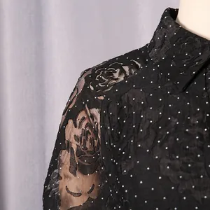 Detail view of black floral embroidery and sequins on an elegant dress shoulder
