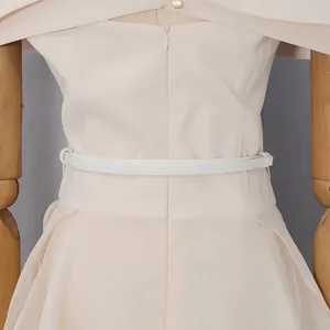 Dettaglio vita vestito crema elegante con cintura bianca sottile e cerniera posteriore