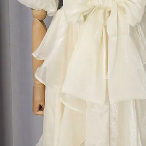 Detailopname van een crème gelaagde maxi-jurk met een elegante strik en glanzende stof