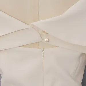 Dettaglio di abito crema elegante con bottoni dorati e cerniera posteriore a scomparsa