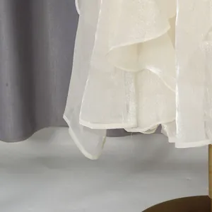 Detailweergave van de glinsterende rucheszoom aan een elegante crème zomerjurk