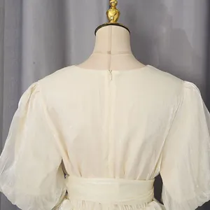 Detailopname van een elegante beige jurk met glanzende stof en blinde rits