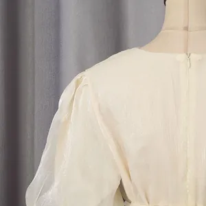 Detailopname van glanzende beige jurkstof met onzichtbare rits aan de achterkant