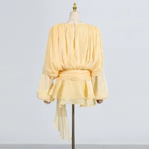 Rear view of elegant pleated yellow dress with waist tie and lantern sleeves.