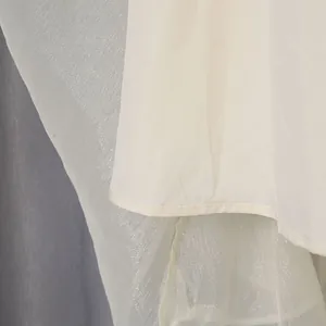 Macrodetail van een elegante crème maxi-jurk die stoftextuur en voering toont.