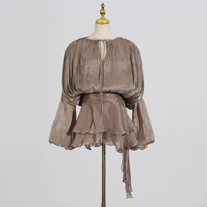 Close-up detail of elegant brown pleated mini dress with ruffles and a tie-waist design