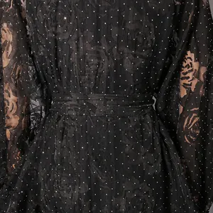 Close-up detail of black floral print dress with small white polka dots and waist tie