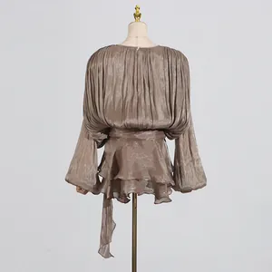 Back view of elegant pleated blouse with ruffles and waist tie in champagne brown.