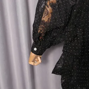 Detailed view of elegant black floral dress sleeve featuring a decorative sparkling cuff button