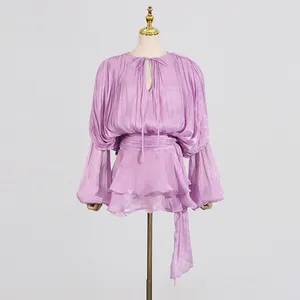 Close-up view of elegant purple pleated mini dress featuring a tie-neck and chic tiered hem