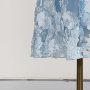 Dettaglio del ricamo di fiori 3D su un abito da festa estivo azzurro in stile francese