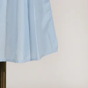Dettaglio dell'orlo in tessuto azzurro e delle cuciture di un abito senza maniche stile francese