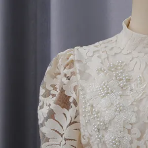 Gros plan d'une robe en dentelle crème avec broderie florale et perles élégantes