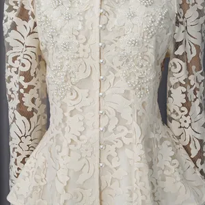 Détail d'une robe en dentelle beige élégante avec boutons de perles et broderies