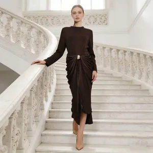 Elegant brown long-sleeved bodycon midi dress with front draped waist detail on stairs.