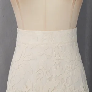 Détail de la broderie en dentelle crème sur la jupe taille haute d'un ensemble deux pièces.