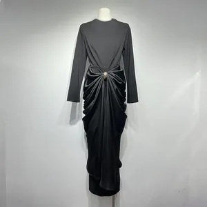 Detail showing elegant black long-sleeved dress with draped waist and gold brooch
