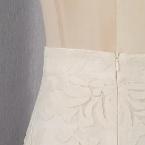 Détail d'un ensemble jupe en dentelle blanche avec fermeture éclair invisible et broderie florale.