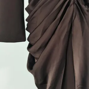 Close-up view showing the elegant ruched draping detail on a brown satin bodycon dress.