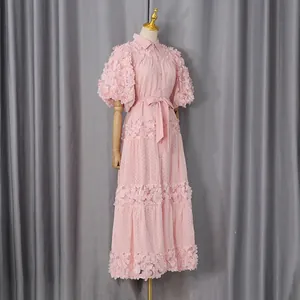 Dettaglio di un abito boho rosa con intricati decori floreali 3D e cintura in vita.