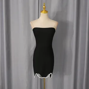 Detailopname van een zwarte bodycon tube-jurk met decoratieve parelzoom op mannequin