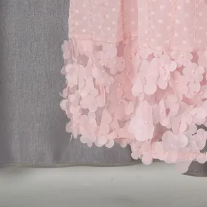 Dettaglio ravvicinato delle applicazioni floreali 3D sull'orlo di un vestito rosa.