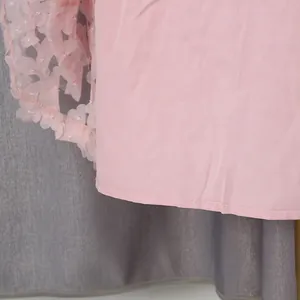 Dettaglio di abito bohémien rosa con applicazioni floreali e trama della fodera.