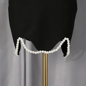 Close-up van een zwarte rokzoom met elegante witte parelkralen als verfijnde afwerking