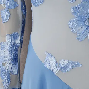 Primo piano di un elegante abito in rete azzurro con ricami floreali 3D e raso lucido