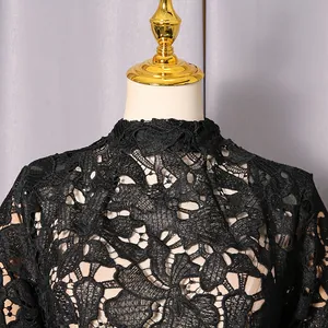 Detailed close-up view of black lace dress with hollow floral patterns and high neckline
