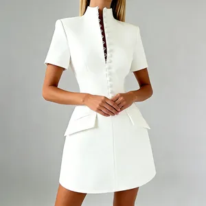 Detalle de vestido ajustado blanco con cuello alto abotonado y solapas de bolsillos.