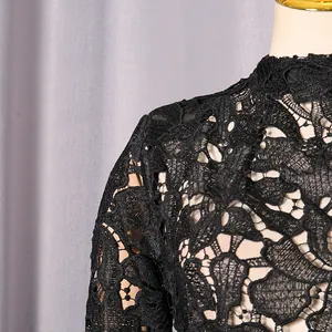 Detailed close-up of delicate black floral lace fabric on a women's dress shoulder.