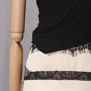 Close-up detail of delicate black lace trim on a sexy cream and black waist-hollow dress.