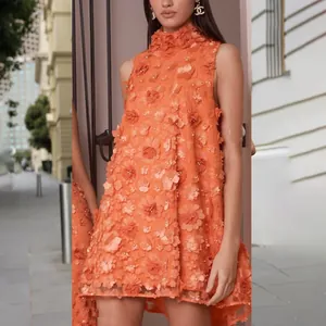 Detailed view of orange dress with 3D floral appliqués and pearl accents