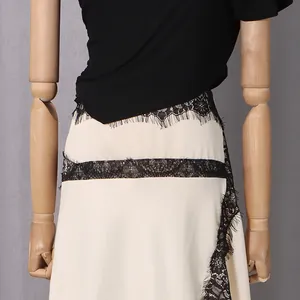 Close-up detail of black eyelash lace trim on cream-colored dress fabric texture