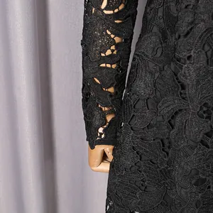 Close-up of black lace dress detailing intricate hollow flower patterns and sleeve texture.