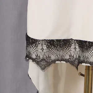 Close-up detail of white dress hem with elegant black eyelash lace trim