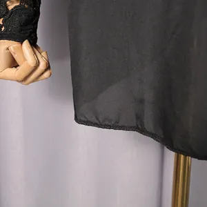 Detail of black dress featuring hollow-out floral lace sleeve and smooth hem finish