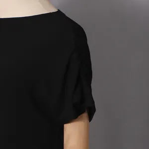 Detailed close-up of pleated shoulder and ribbed texture on an elegant black dress