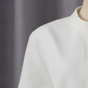 Detalle del cuello alto y las costuras del hombro de un vestido blanco de estilo francés
