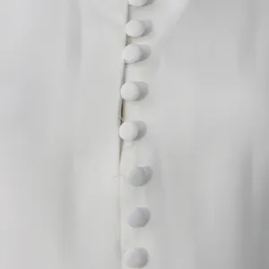 Primer plano de elegantes botones de tela blanca en un vestido corto de estilo francés