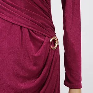 Detailed close-up of a burgundy pleated dress featuring a golden crescent waist buckle.
